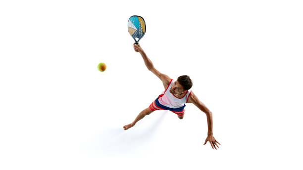 一名身穿红蓝相间运动服的男子正在打壁式网球，照片从上方拍摄，他挥舞着球，白色背景上的彩色球拍被孤立起来图片下载