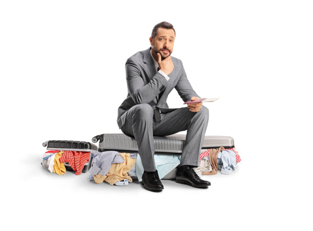一个商人穿着凌乱的衣服坐在一个打包好的行李箱上图片下载