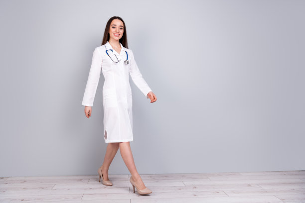 照片中迷人的美女医生穿着白色的医生长袍，孤立在灰色的背景上图片下载