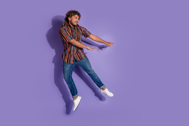 全尺寸照片积极开朗的男人穿着印花衬衫牛仔裤跳跃看着销售空白空间孤立的紫色背景图片下载