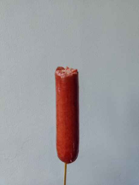 被咬过的香肠融化了的奶酪粘在棍子上，男人拿着它图片下载