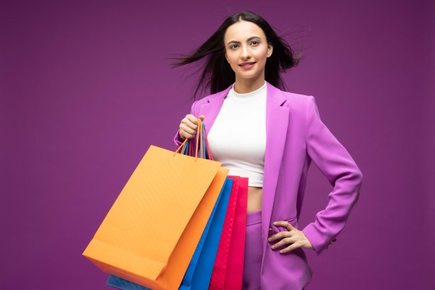 她的肖像，她漂亮的穿着漂亮的迷人的可爱的豪华漂亮开朗的女孩拿着购物袋孤立的紫色背景股票照片图片下载
