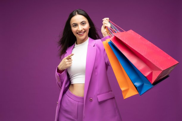 她的肖像，她漂亮的穿着漂亮的迷人的可爱的豪华漂亮开朗的女孩拿着购物袋孤立的紫色背景股票照片图片下载