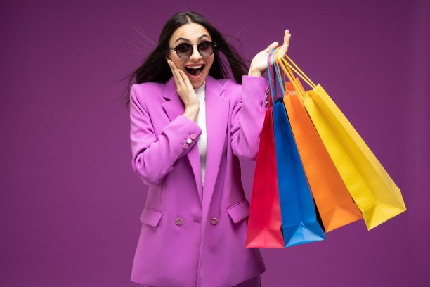 她的肖像，她漂亮的穿着漂亮的迷人的可爱的豪华漂亮开朗的女孩拿着购物袋孤立的紫色背景股票照片图片下载
