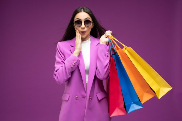 她的肖像，她漂亮的穿着漂亮的迷人的可爱的豪华漂亮开朗的女孩拿着购物袋孤立的紫色背景股票照片图片下载