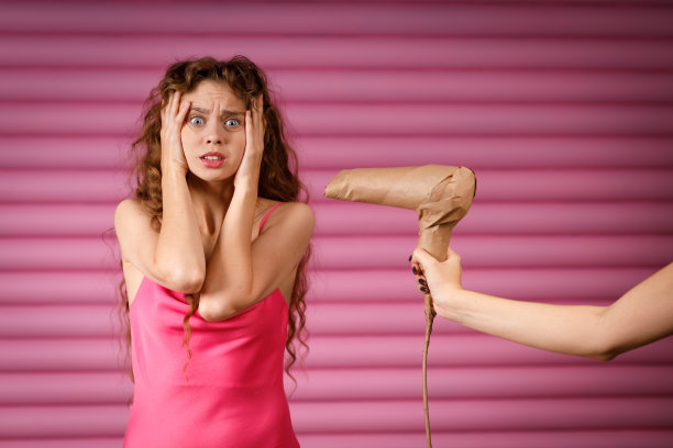 年轻的积极微笑的女人收到惊喜的礼物手持电吹风包裹在质朴的米色工艺纸包。黑色星期五概念图片下载