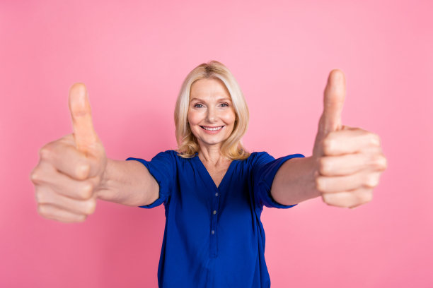 漂亮的高级女性的照片肖像赞穿时髦的蓝色服装孤立在粉红色的背景图片下载