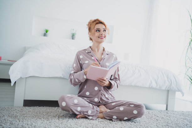 可爱的漂亮女人的照片，穿着睡衣，拿着书，舒适的卧室，白色的日光房间，室内图片下载