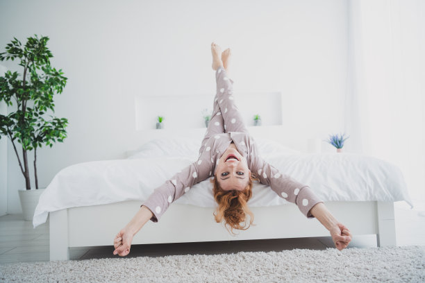 照片积极的好心情的女人睡衣微笑放松床颠倒在室内的房子公寓房间图片下载