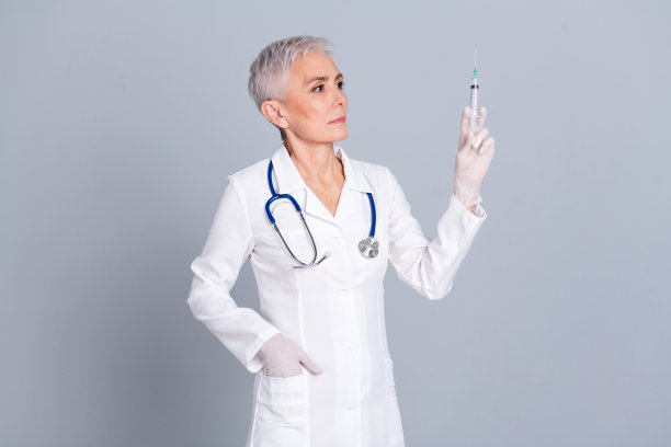 照片自信的女专家穿着白色长袍注射疫苗隔离在灰色背景图片下载