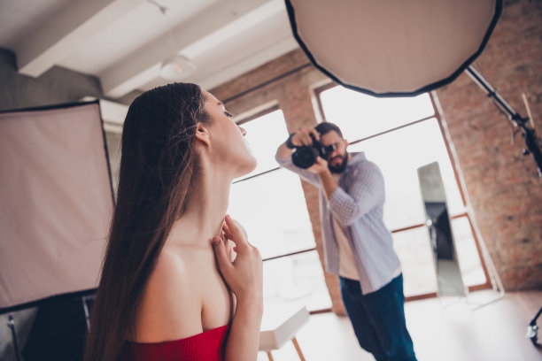 照片的专业摄影师拍摄可爱的女士穿红色礼服在室内工作室的工作场所图片下载