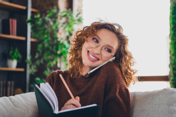可爱的成功女人的照片，穿着时髦的衣服，拿着计划者在家工作，在家里写计划任务图片下载