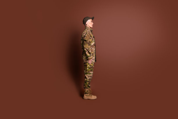 照片中坚强严肃的老妇人穿着迷彩制服与敌人战斗，空白空间孤立的棕色背景图片下载