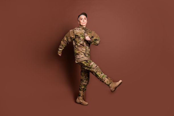 成年女性勇敢的女军人行军行走穿着迷彩军服孤立的棕色背景照片图片下载