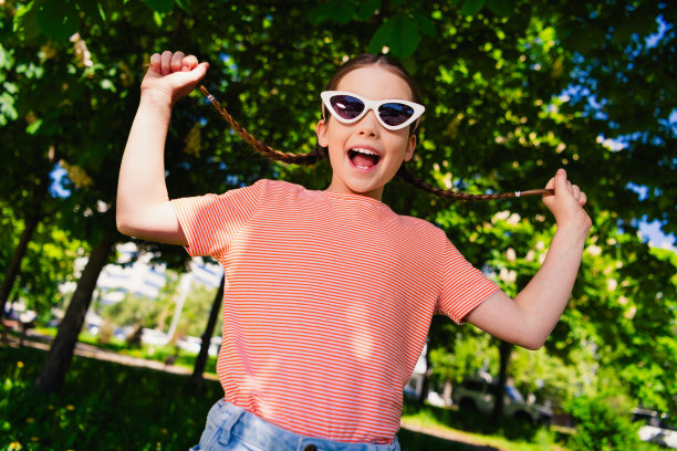 肖像积极开朗快乐的小女孩微笑夏天拉辫子有乐趣好心情周末享受户外公园外街道图片下载