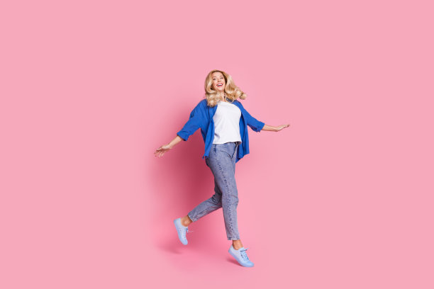 全尺寸照片心情好的女人穿着蓝色衬衫牛仔裤子飞跑购物到空旷的空间孤立在粉红色的背景图片下载