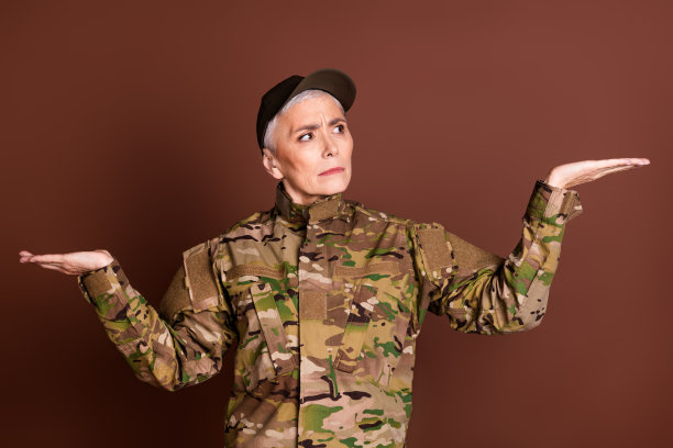 退休妇女职业军官的照片不确定比较看空穿着迷彩服孤立在棕色背景上图片下载