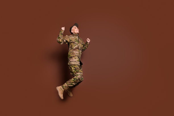 可爱的退休女士的全身照片专业军官跳赢穿着迷彩军装孤立的棕色背景图片下载