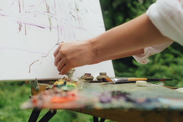 近距离的妇女的手与画笔和油漆附近的画布练习曲。正念，艺术疗法，创意概念。在大自然中进行空气绘画的过程。一系列的照片展示了一幅画的一步一步的创作图片下载