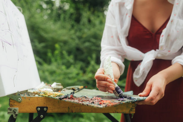 近距离的妇女的手与画笔和油漆附近的画布练习曲。正念，艺术疗法，创意概念。在大自然中进行空气绘画的过程。一系列的照片展示了一幅画的一步一步的创作图片下载