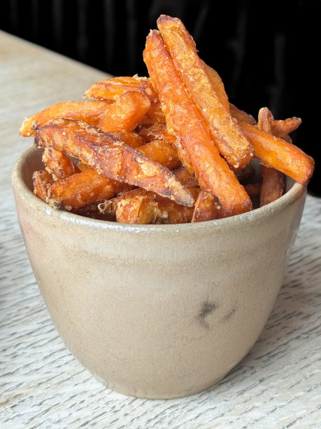 特写图片:脆脆的甘薯片作为酒吧小吃，酒吧食品在锅里，脆脆的甘薯薯条煮在皮上，一天五次饮食和更健康的饮食理念图片下载