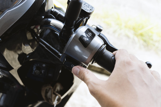 特写手启动摩托车发动机，捕捉车把和点火开关的细节，完美的汽车和交通主题。图片下载