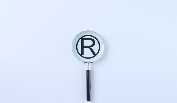 注册商标版权标志。放大镜聚焦在白色背景上的注册商标符号，说明商标注册和知识产权的概念。图片下载
