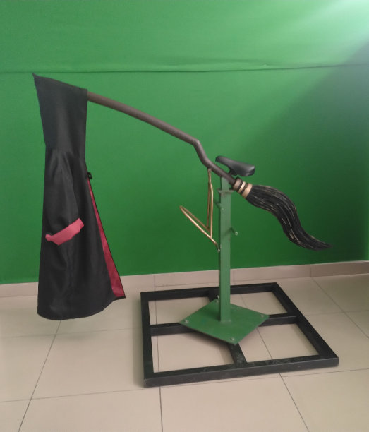 绿色背景上的女巫扫帚和斗篷的金属雕塑图片下载