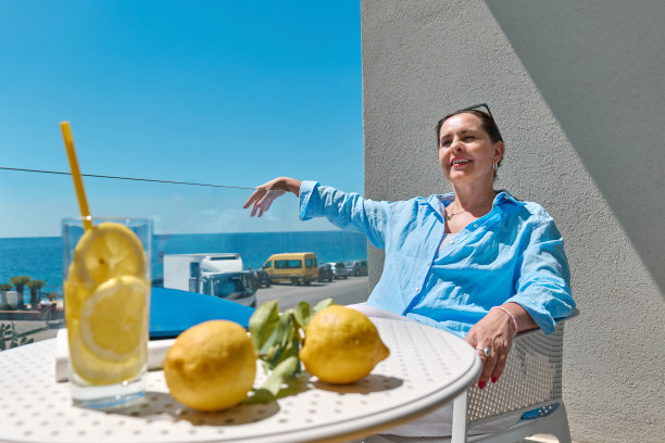 满足的女人在夏天放松在酒店的阳台上，凝视着大海。在地中海放松和暑假的概念。图片下载