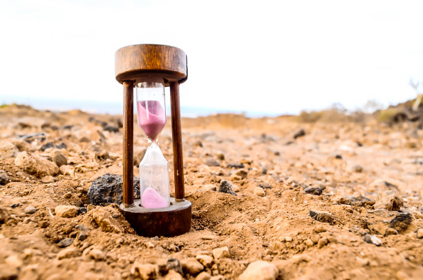 一个沙子计时器正坐在岩石表面上图片下载