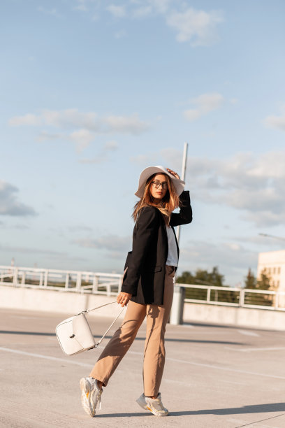 漂亮优雅的年轻女子穿着时尚的商务休闲装和鞋子走向商场。在阳光明媚的夏日，时尚女孩在户外停车。优雅的外观。青春的风格。图片下载