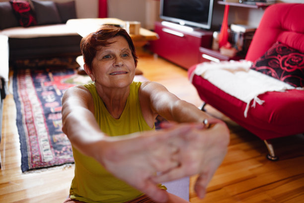 退休后的运动。快乐的老年妇女在家锻炼时做柔韧性练习，以获得更健康的生活图片下载