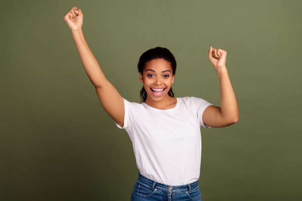 年轻美丽的美国运动女士的肖像照片在白色t恤获胜者庆祝孤立的卡其色背景图片下载