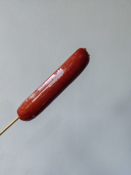 香肠融化奶酪粘在棍子上，由男性手握着图片下载