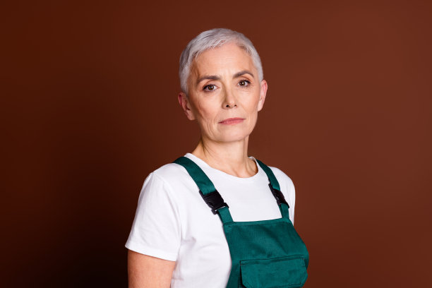 高级女专业建筑工人的照片穿着制服孤立的棕色背景图片下载