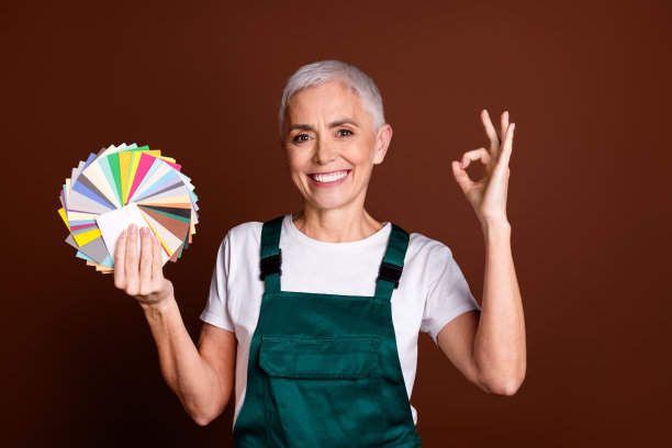 照片中，风趣迷人的资深女性穿着绿色制服，标志孤立在棕色背景上图片下载