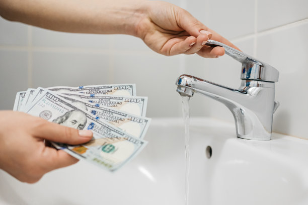 女人在家里用手关掉水龙头，数着省下的钱。节约资源和水电费的概念。图片下载