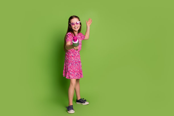 可爱的女学生的全尺寸照片给麦克你唱空空间穿粉红色的衣服孤立在绿色的背景图片下载