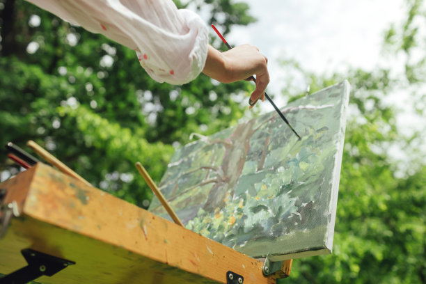 近距离的妇女的手与画笔和油漆附近的画布练习曲。正念，艺术疗法，创意概念。在大自然中进行空气绘画的过程。一系列的照片展示了一幅画的一步一步的创作图片下载