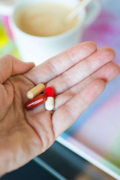 白人女性早餐时手拿药片的特写图片下载