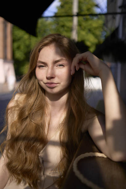 一个漂亮的十几岁的女孩坐在外面的酒吧里，穿着一件桃红色的绒毛西装和一件旧式的马甲图片下载