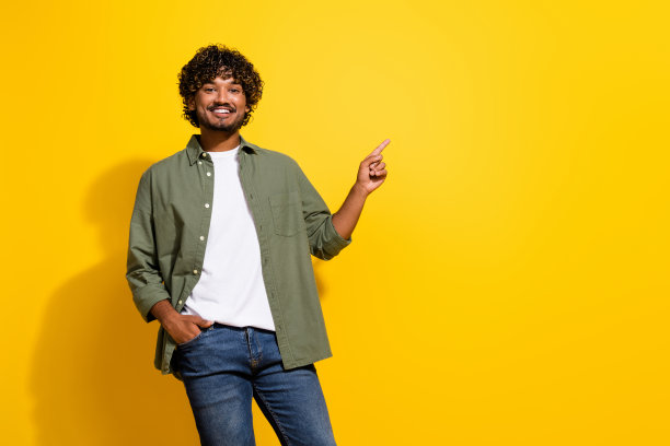 年轻的西班牙人的肖像照片在卡其色衬衫推荐超市交易廉价产品孤立的黄色背景图片下载