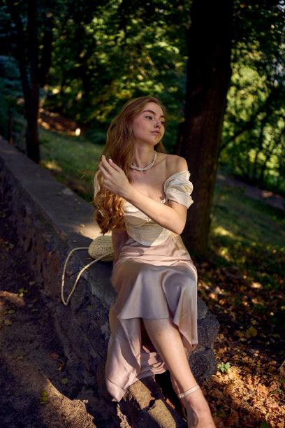 一个漂亮的十几岁的女孩，穿着丝绸裙和紧身胸衣，在公园里和河边散步图片下载