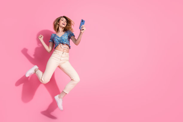 迷人的年轻女子的全身照片，手持跳绳装置，身穿蓝色印花衣服，孤立在粉红色的背景上图片下载