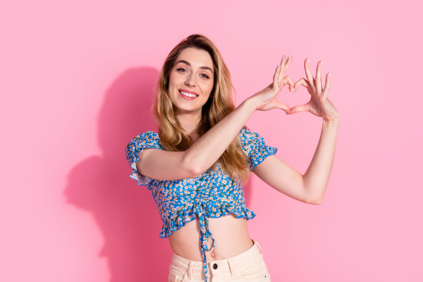 照片中迷人的年轻女子穿着时髦的蓝色印花衣服，在粉红色的背景上显得很有爱心图片下载