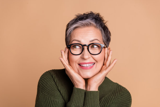 照片的好女人与短头发穿着毛衣在眼镜手臂在脸颊上看标志空白空间孤立的米色背景图片下载