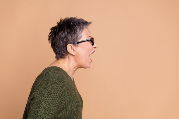 侧面侧面照片的愤怒的专横的女人与短头发，穿着毛衣大声尖叫的空白空间孤立的米色背景图片下载