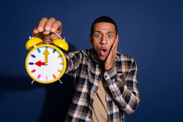 时髦印象深刻的家伙穿着格子衬衫的照片，显示你的时钟空白空间孤立的蓝色背景图片下载