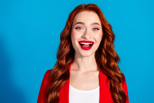 照片中，惊喜快乐的女孩穿着红色时尚的衣服，孤立在蓝色的背景上图片下载