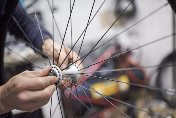 一名男子正在组装自行车轮轴，这是自行车维修服务的一部分。图片下载